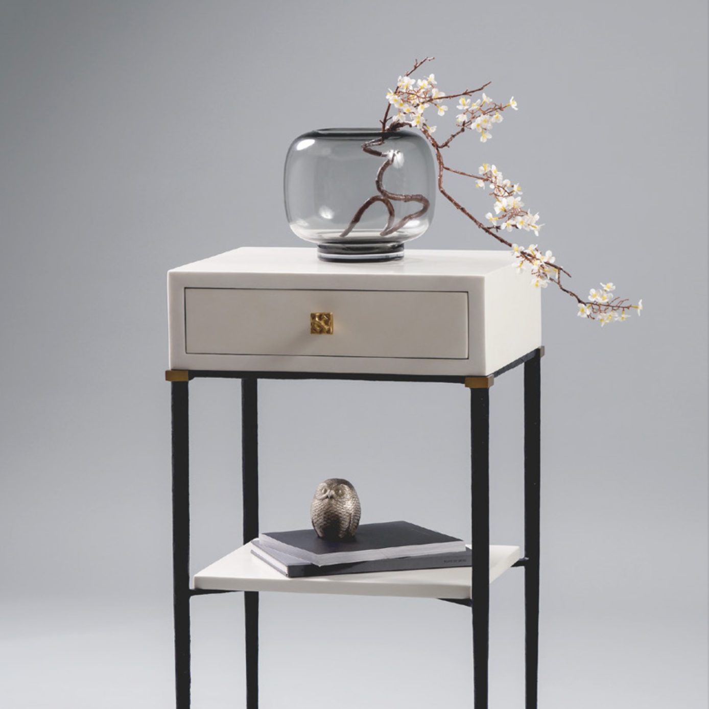 Luxury bedside table with a glass vase and decorative branch on a gray background
