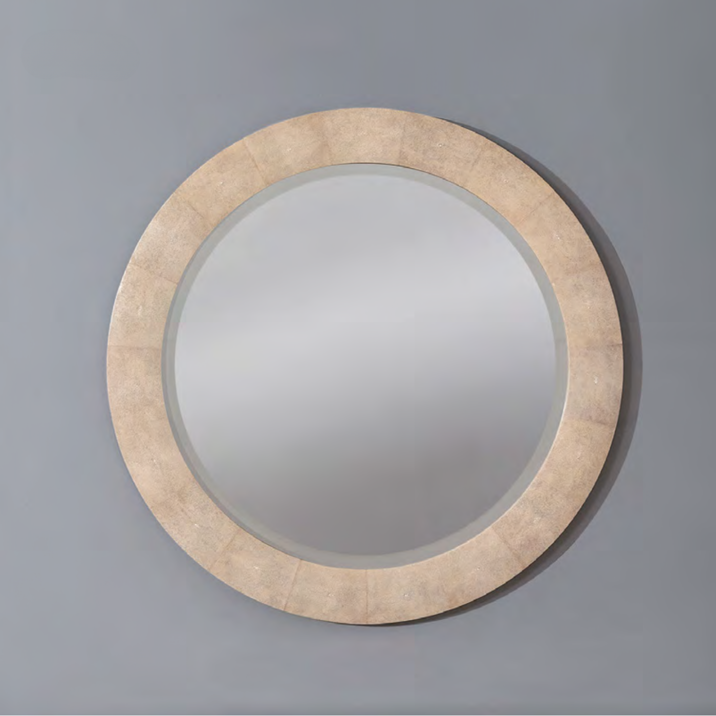 Round mirror with natural shagreen frame on a gray background